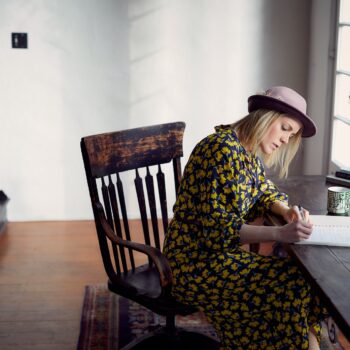 artist writing copy woman wearing a hat sitting at a desk writing