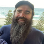 Man with beard in front of the beach