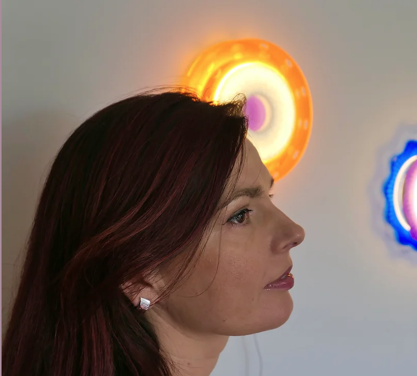 Image of Artist Luiza Milewicz side profile in front of light artworks