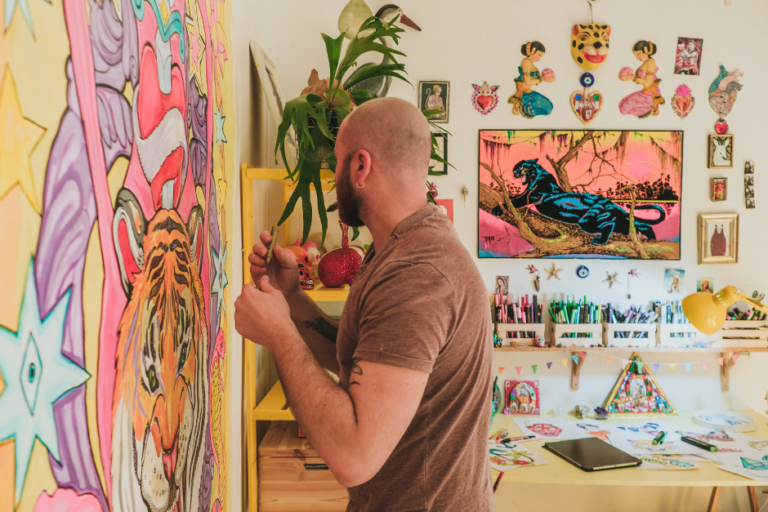 man with beard and bald head looking away as he works on a bright pop artwork